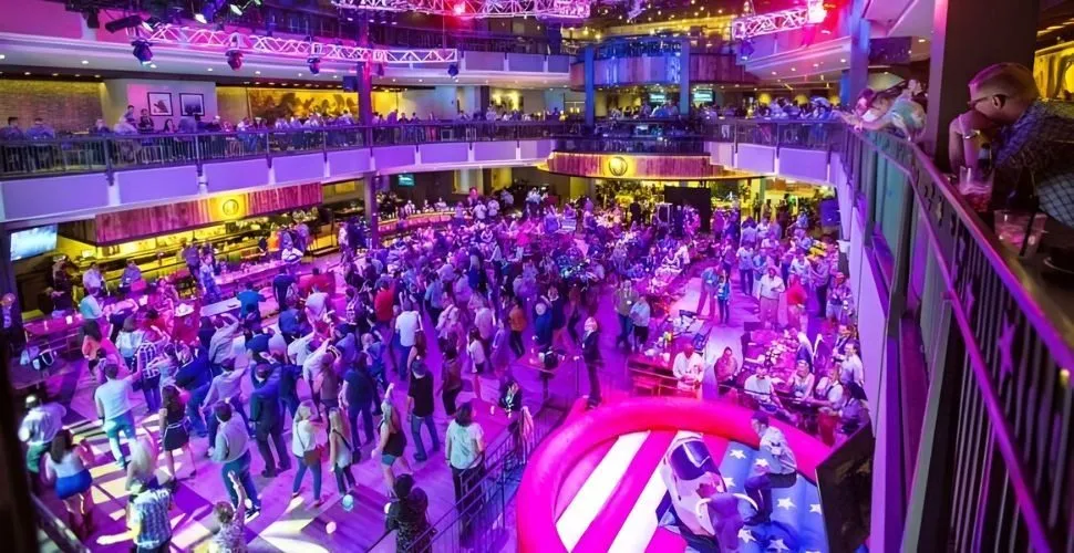 Crowd of guests on a lit dance floor at a large venue party