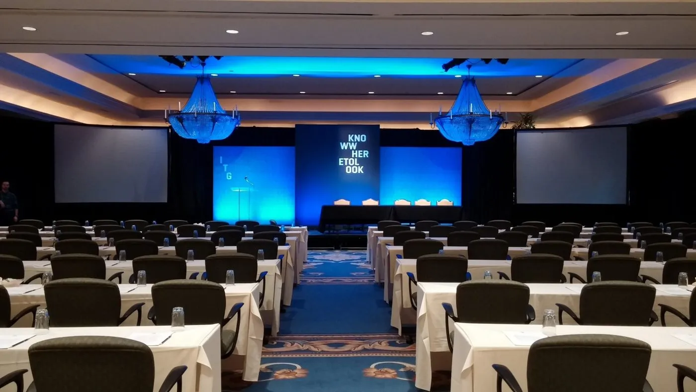 Corporate general session with stage screens and tables of attendees