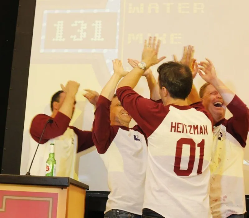 Group in matching jerseys cheering beside a podium at a company event