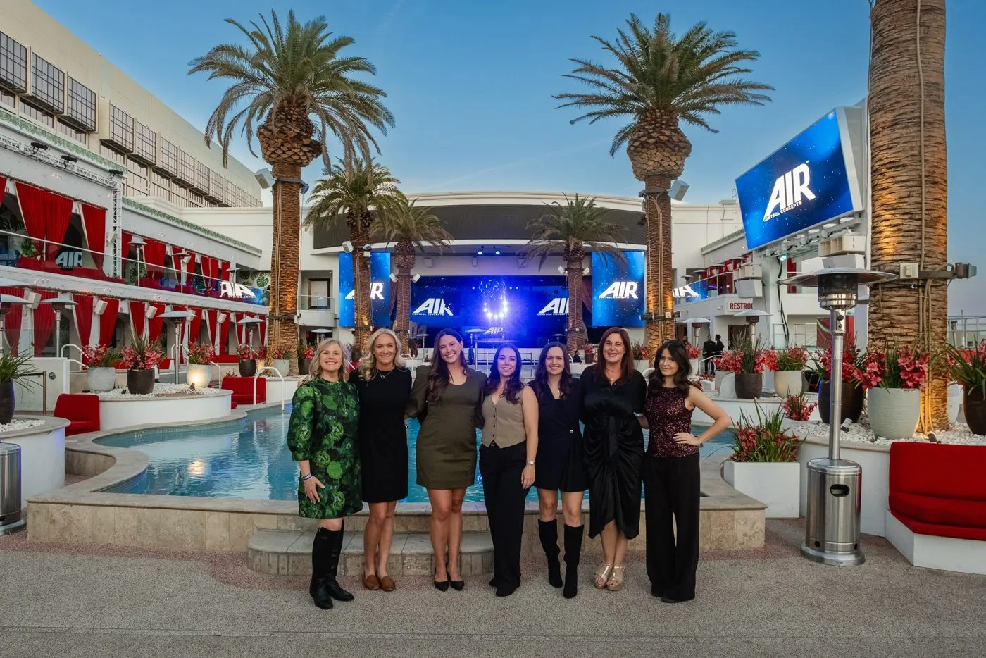Team posed beside a branded sign at a pool deck event venue