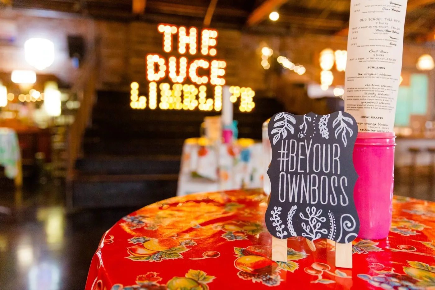 Themed restaurant table with a lit sign and event signage for a sales team dinner