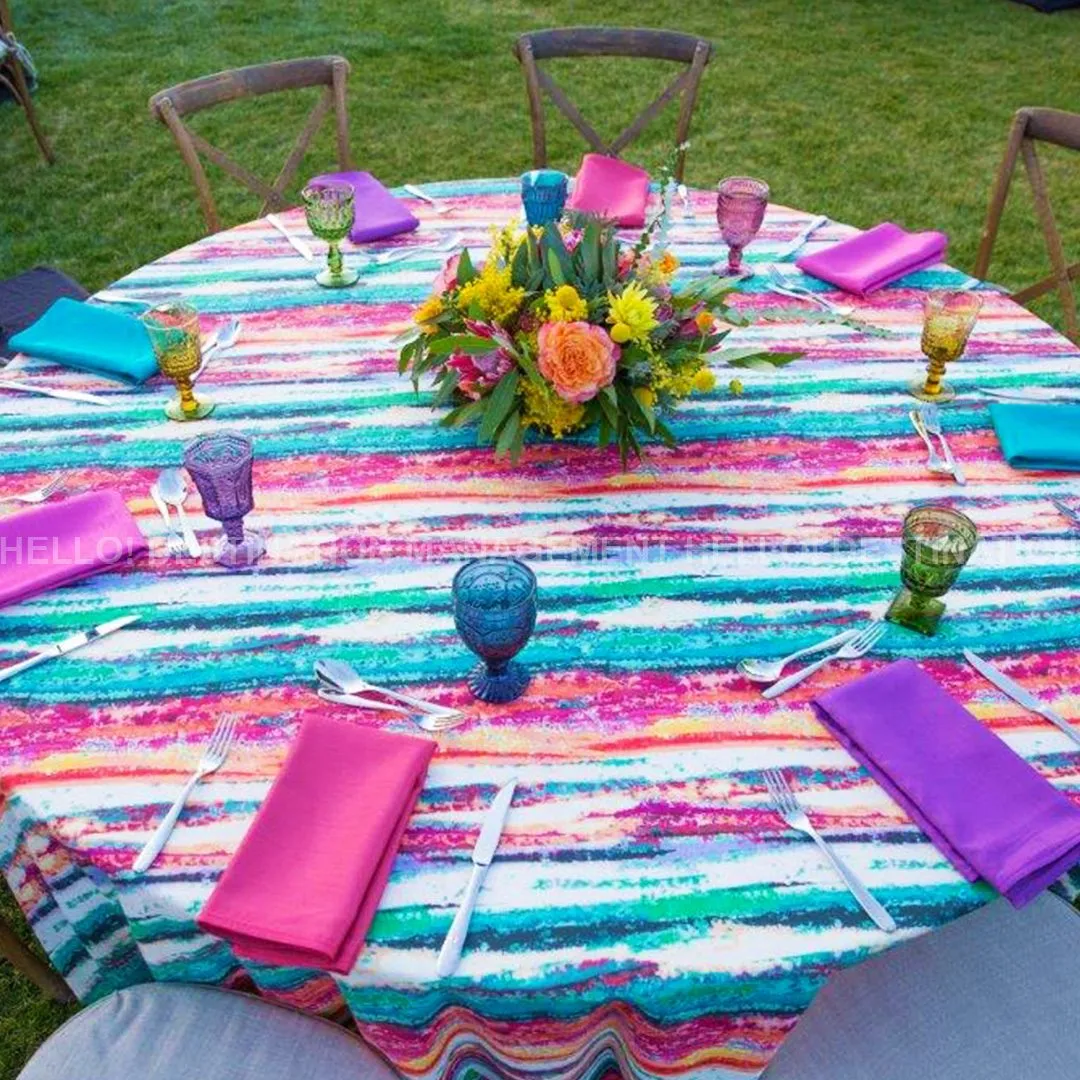 Round table set with a striped cloth, colored napkins and a flower centerpiece