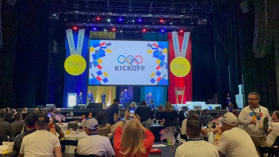Sales kickoff stage with medal-themed banners in front of seated guests
