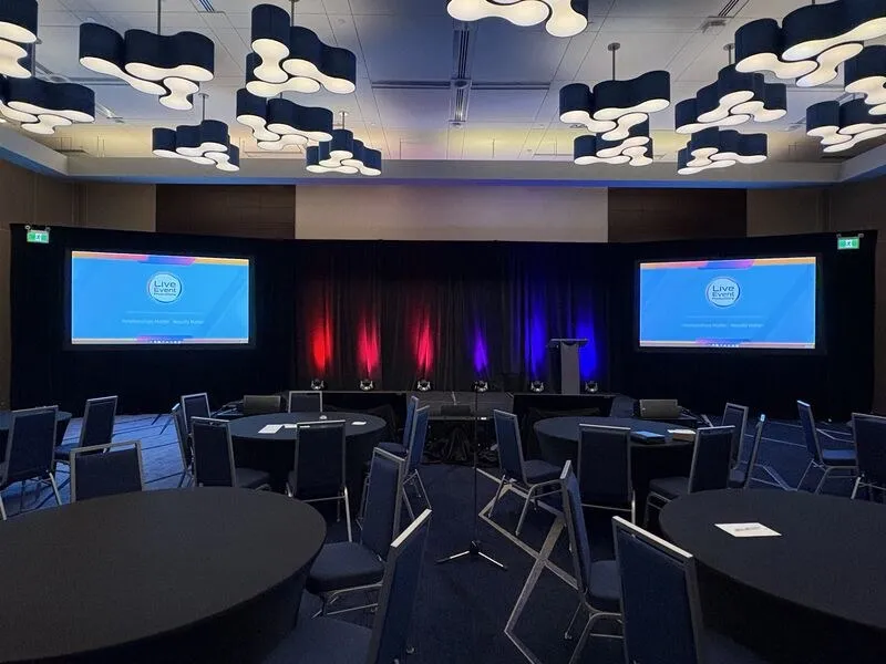 Ballroom general session set with twin screens and stage lighting, by Live Event Productions