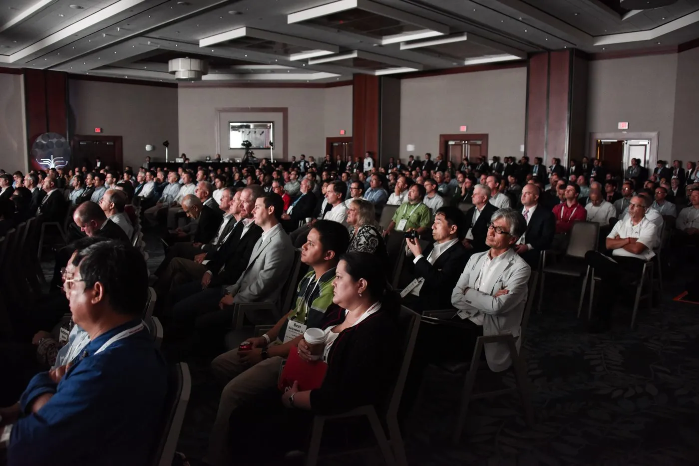 Large audience seated at tables at a corporate conference session