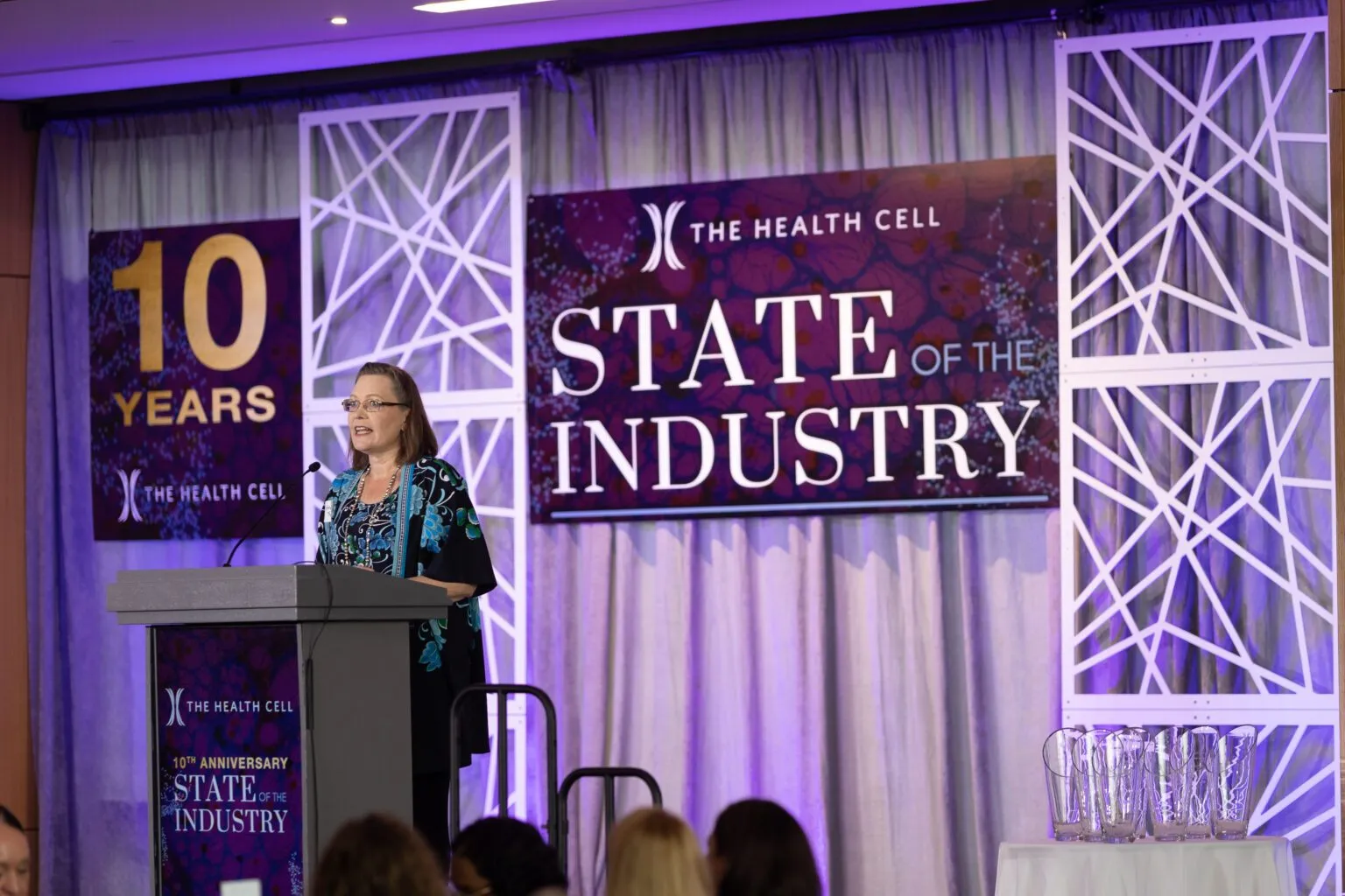 Speaker at a podium on a branded stage at an industry summit