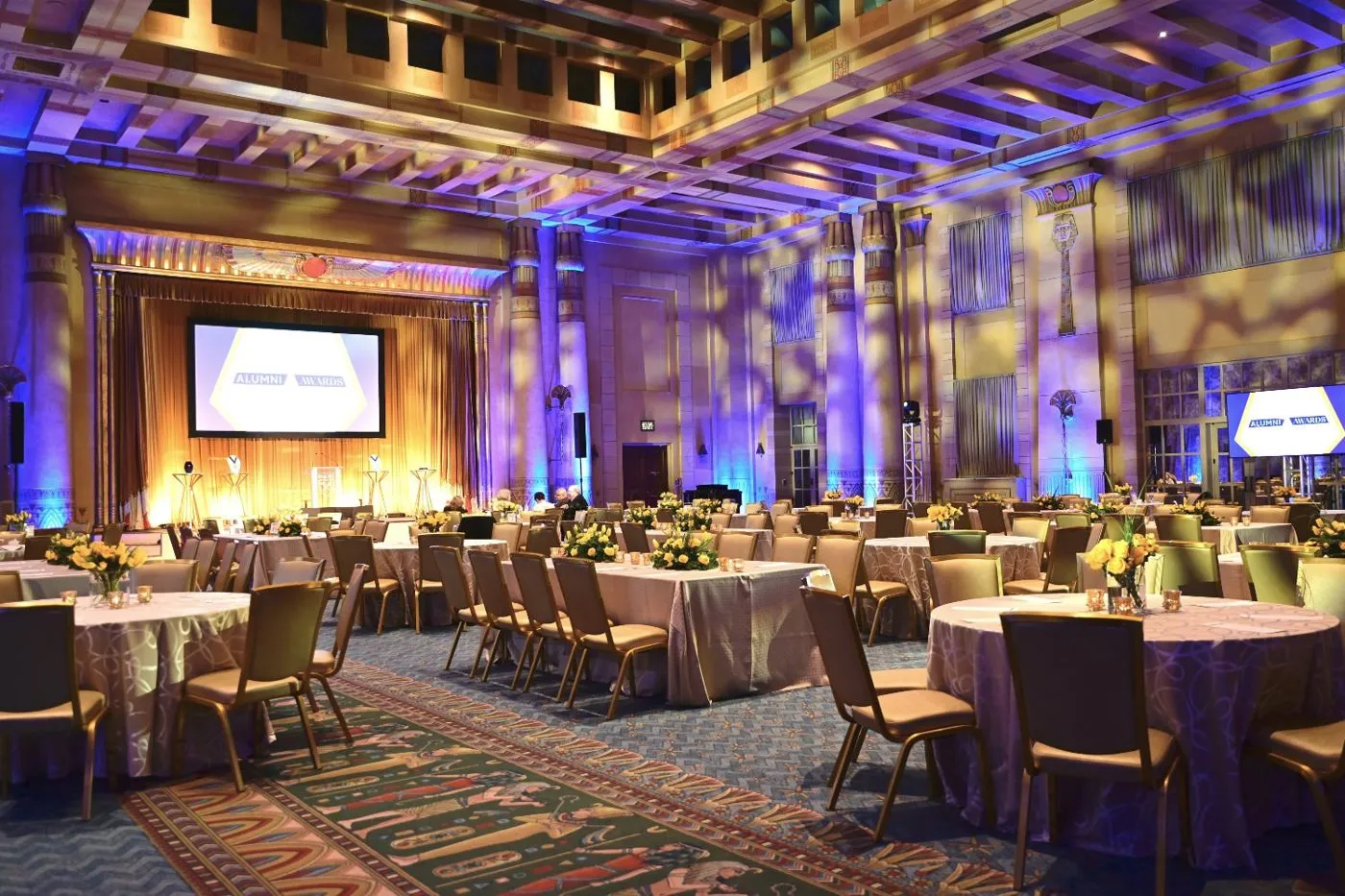 Awards event with dinner tables, screens and stage lighting