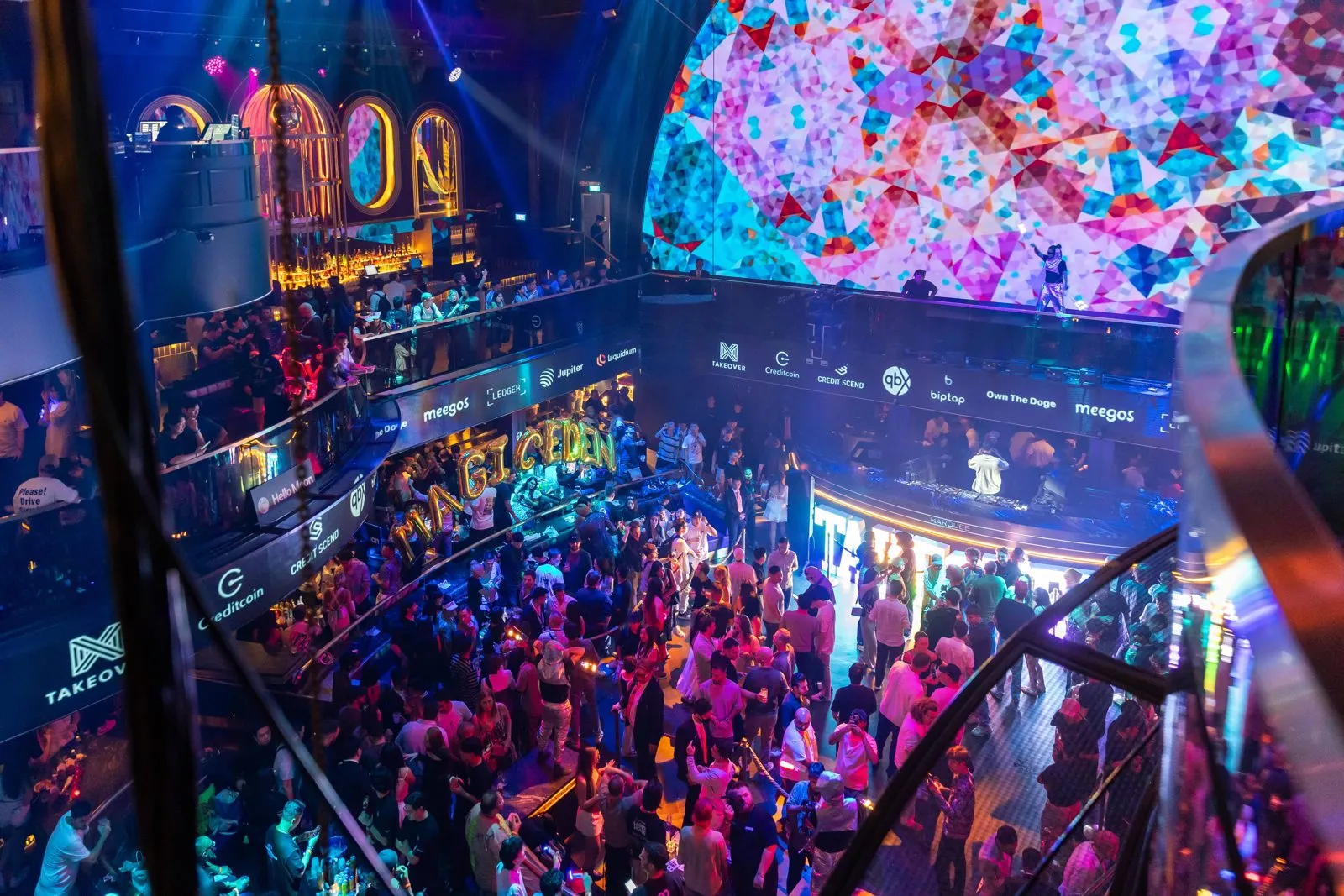 Aerial view of a crowded networking event under a large colorful projection dome