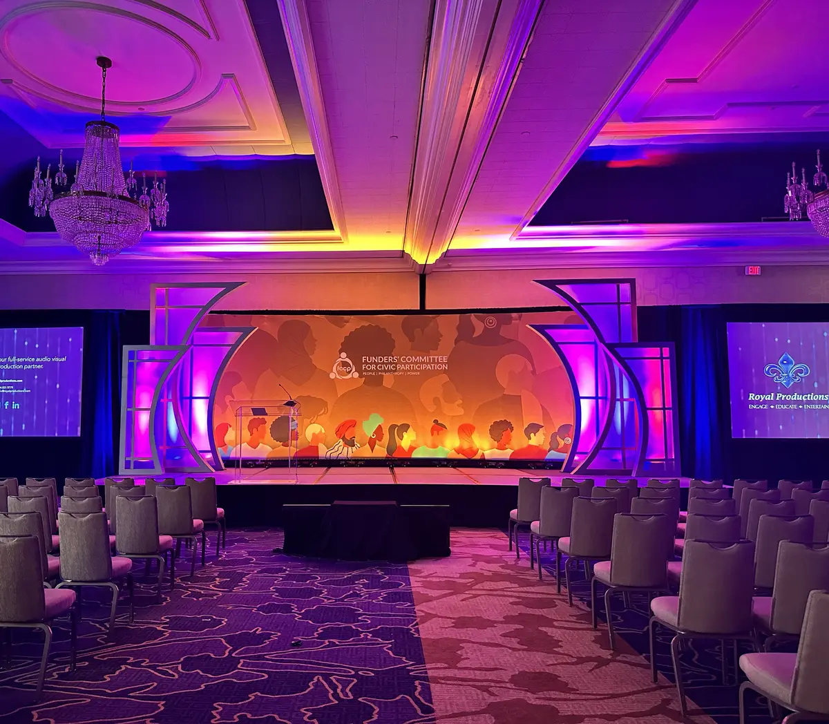 Ballroom set for a conference general session with stage lighting and screens