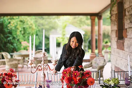 Jennifer Galvez Caton arranging red florals on a porch event table