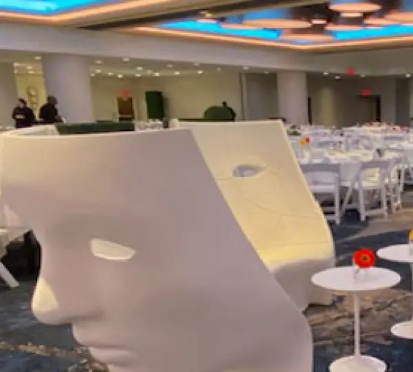 Event space with a sculptural mask installation and cocktail tables