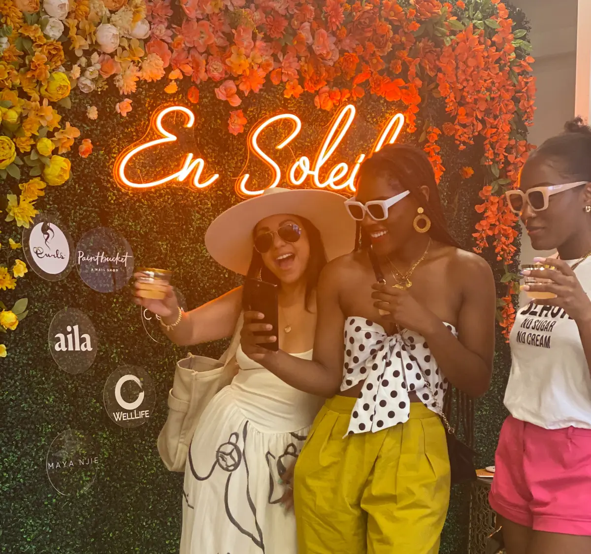 Guests posing at the floral neon wall during the En Soleil launch