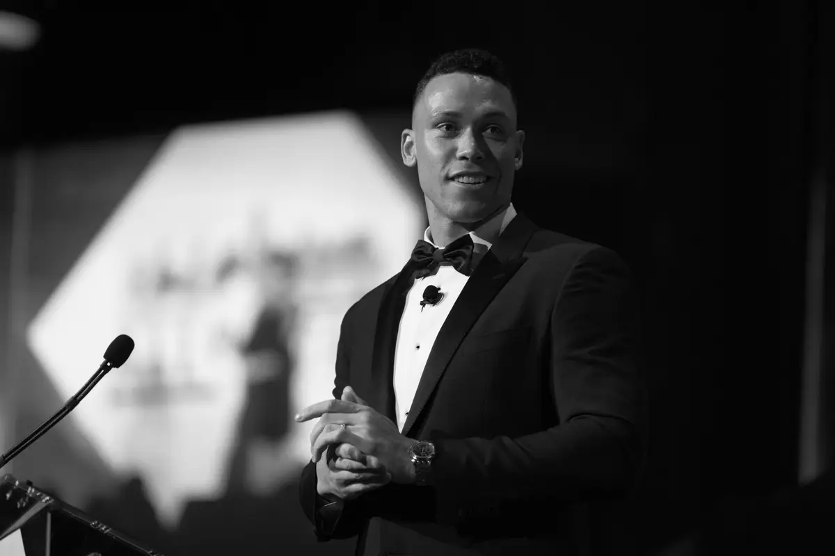 Speaker in a tuxedo addressing guests at a gala