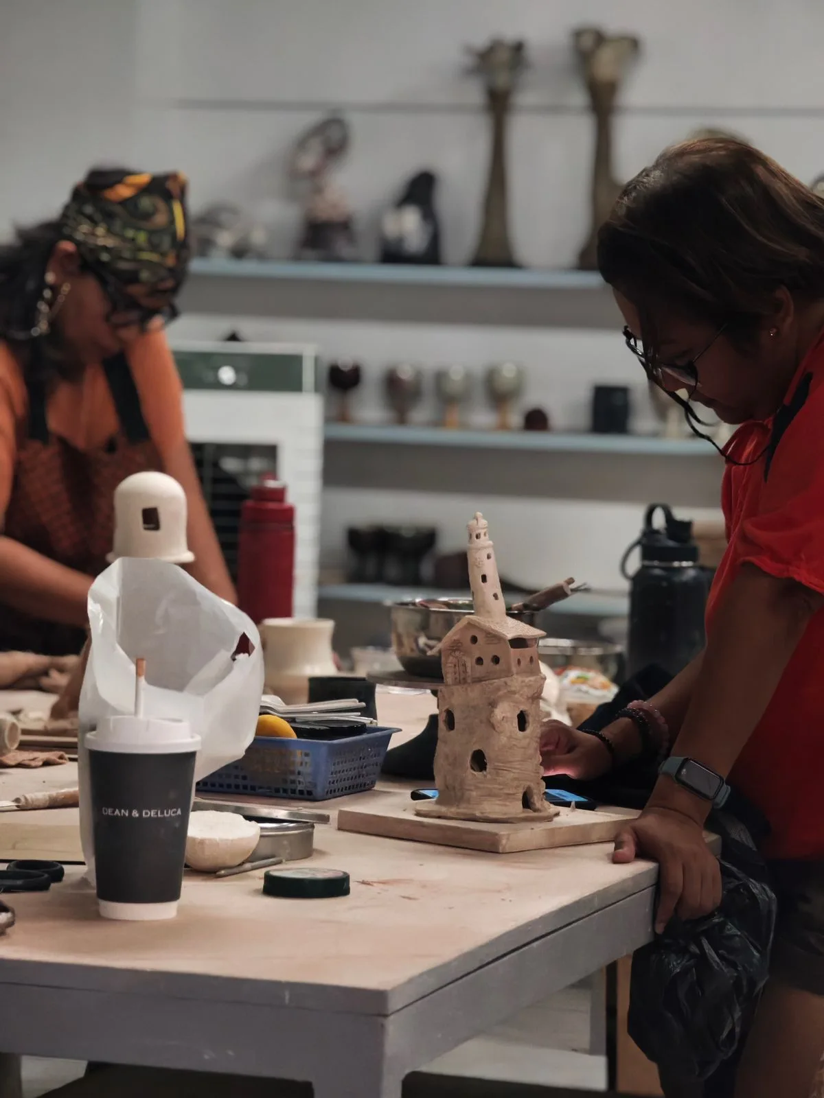 Adults working on pottery pieces at a workshop table