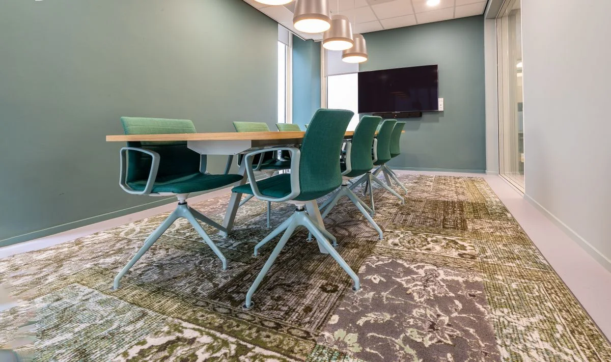 A furnished meeting room with green chairs and a screen