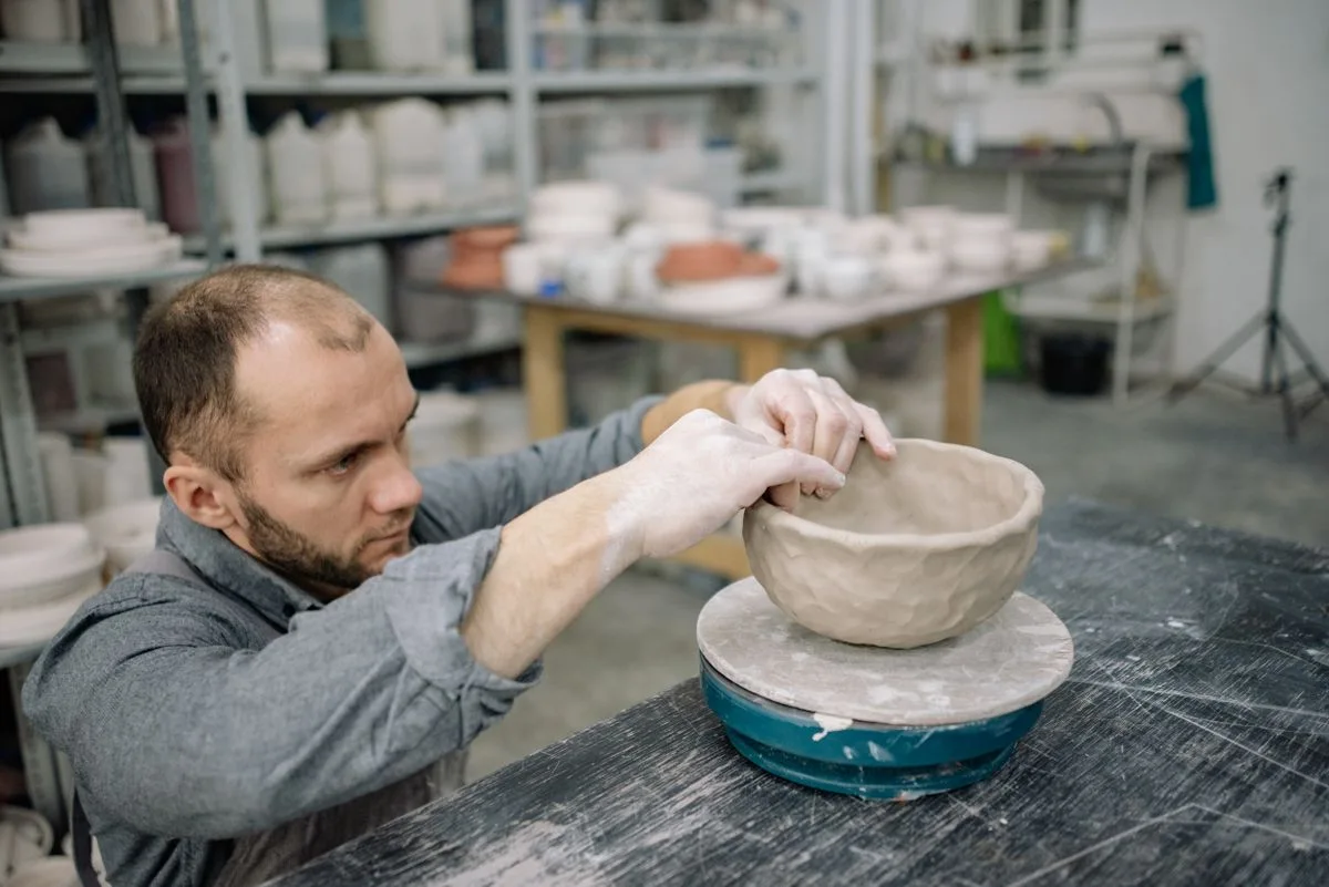 A participant shaping clay at a pottery wheel