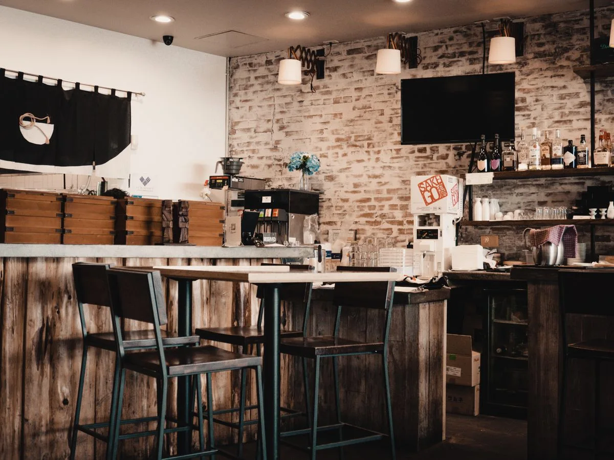A bar interior with brick walls, wooden tables, and a counter