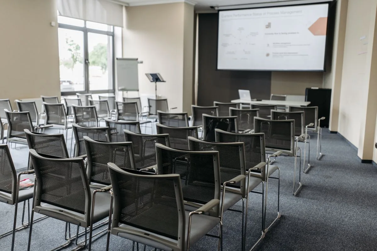 A conference room with rows of chairs and a presentation screen