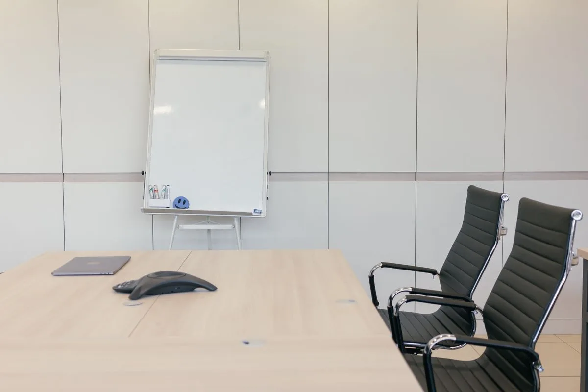 A meeting room with a whiteboard and chairs around a table