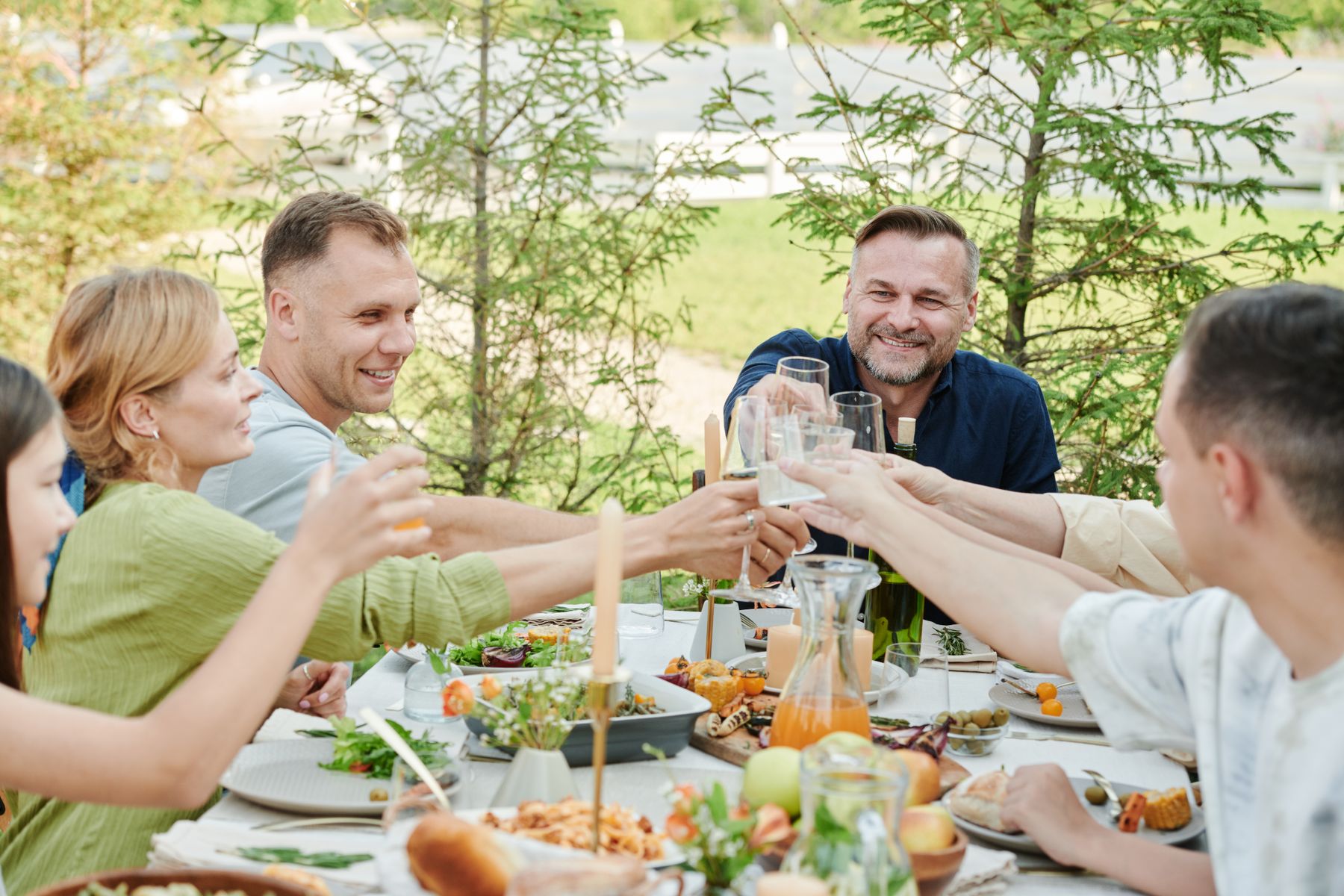 A group raising their glasses over a shared outdoor dinner