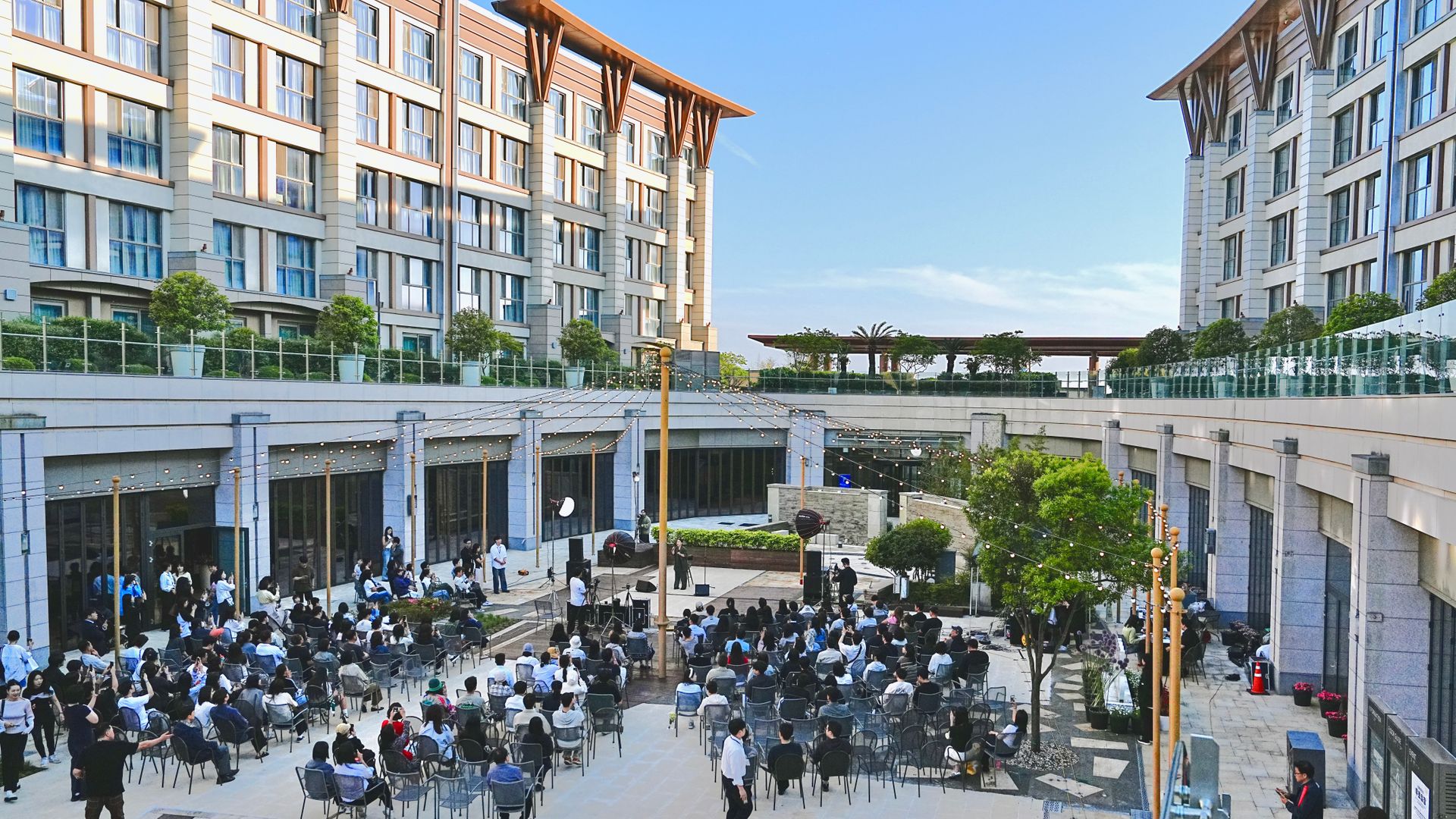 Attendees gathered for an outdoor corporate event in a courtyard beneath string lights