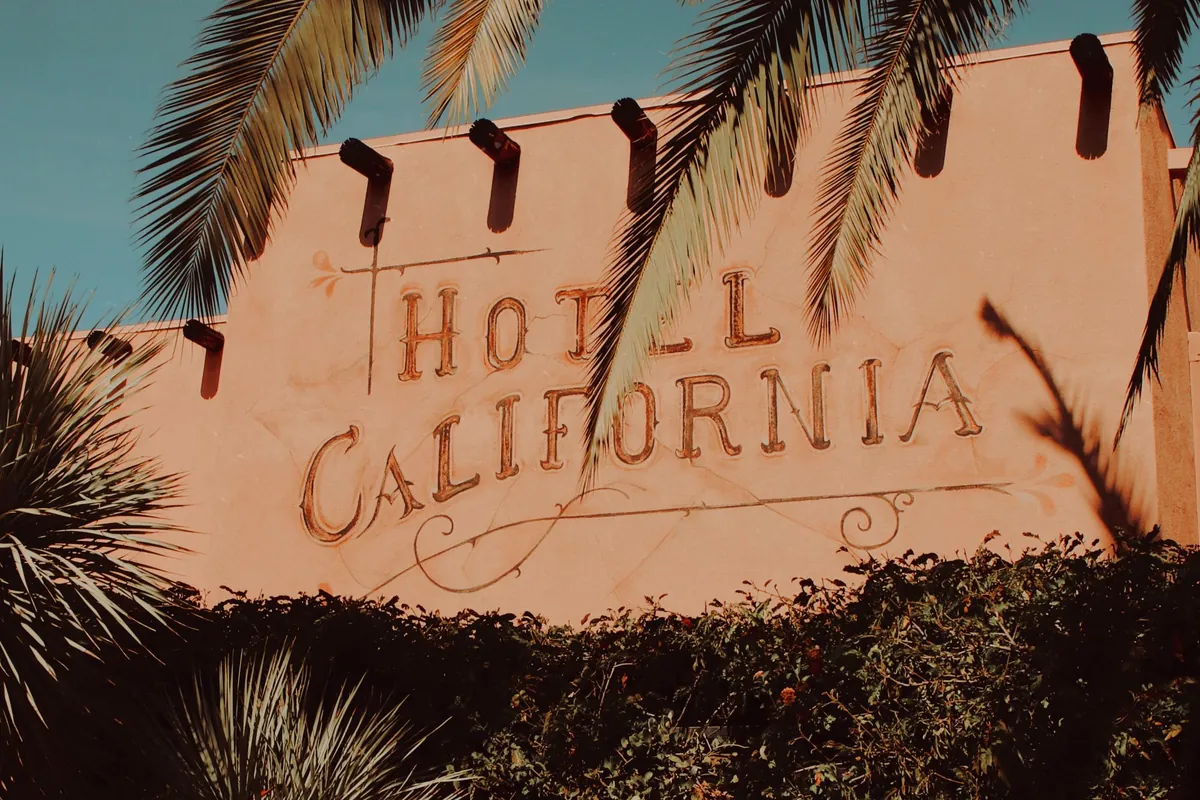 A palm tree in front of the Hotel California in Palm Springs at sunset.