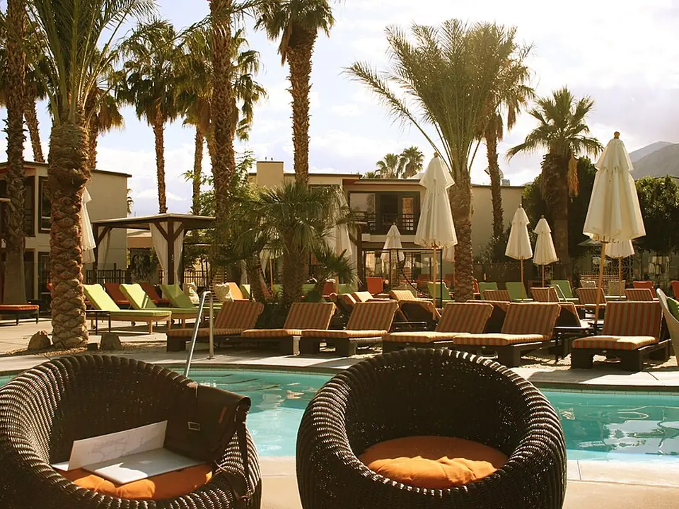 A pool, lounge chairs, and guest-room wings at the Riviera hotel in Palm Springs.