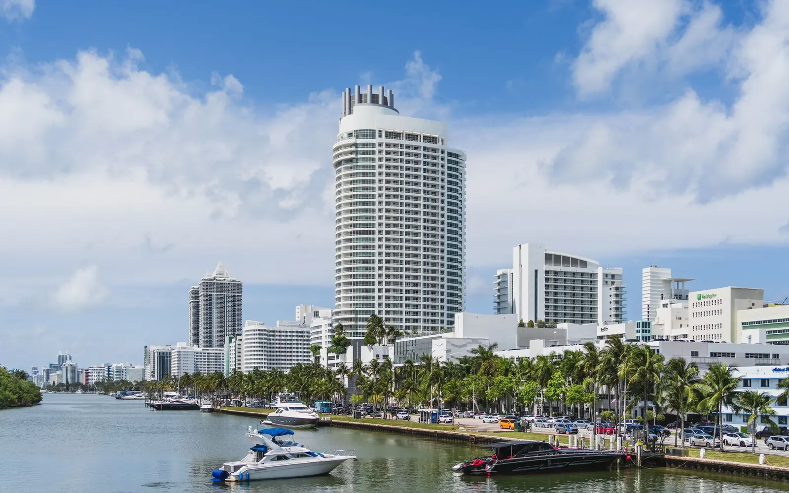 Palm-lined waterfront hotels and boats along a Miami Beach canal.