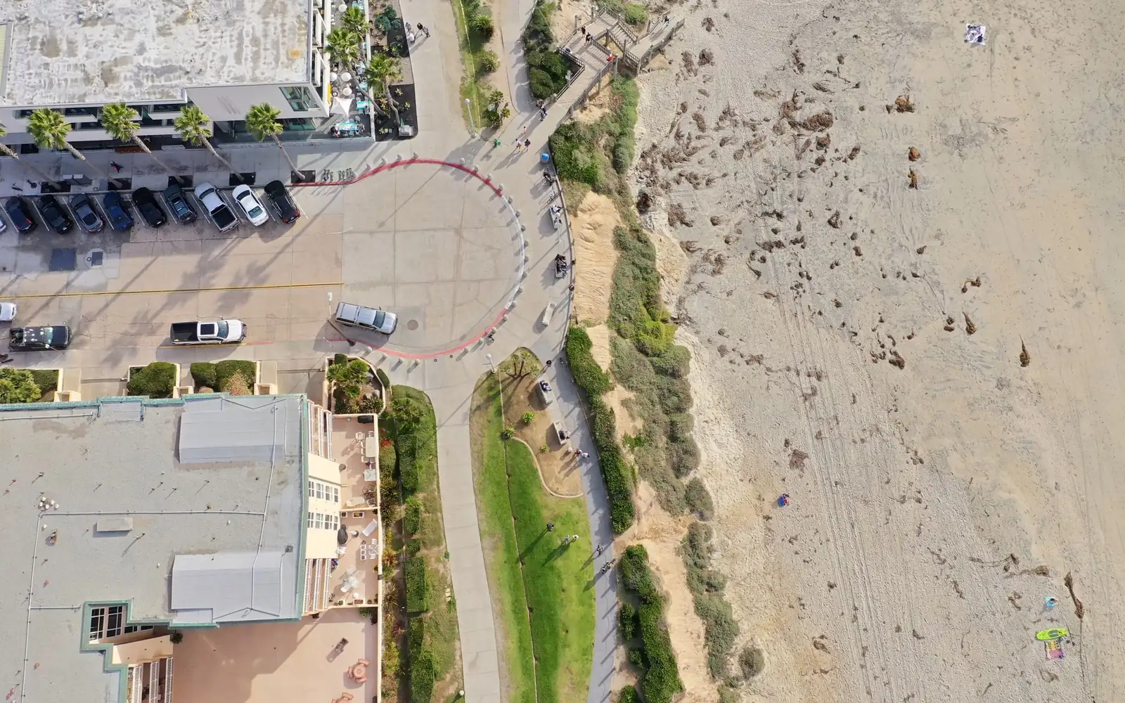 An aerial view of a San Diego beachfront, with a boardwalk, low buildings, and sand.