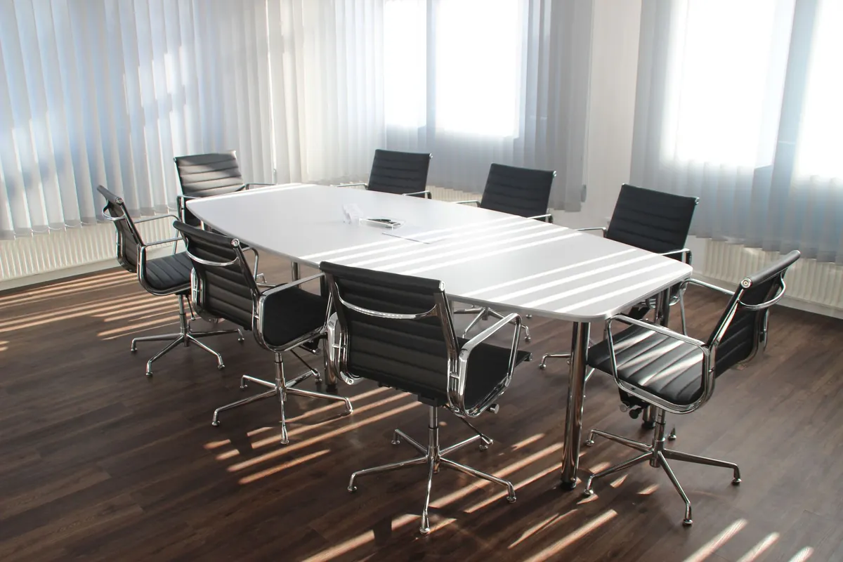 Black chairs around a conference table in a bright meeting room.